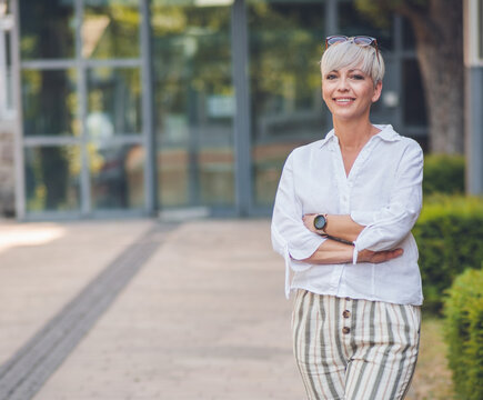 European happy blond adult woman looking to camera. Smiling face of beautiful mid aged female person dressed in white summer shirt.
