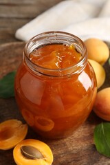 Tasty apricot jam and fresh fruits on wooden table, closeup