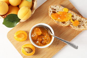 Tasty apricot jam and fresh fruits on white table, flat lay
