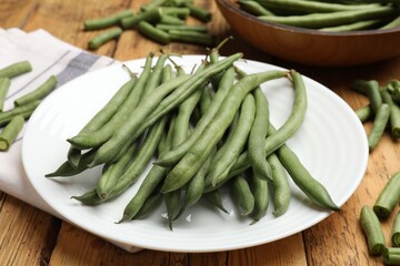 Many raw green beans on wooden table, closeup