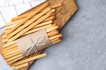 Delicious grissini sticks on grey textured table, top view. Space for text