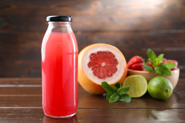 Tasty juice in glass bottle, fresh fruits, strawberries and mint on wooden table