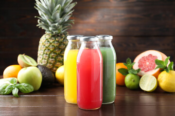 Tasty juices in glass bottles, fresh fruits and mint on wooden table, selective focus
