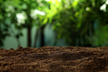 Fertile soil against blurred green background, closeup. Space for text