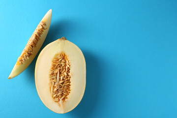 Cut fresh ripe melon on light blue background, flat lay. Space for text