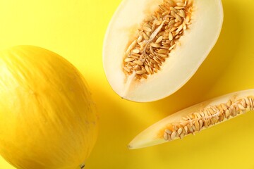 Whole and cut ripe melons on yellow background, flat lay