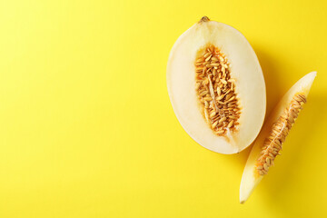 Cut fresh ripe melon on yellow background, flat lay. Space for text