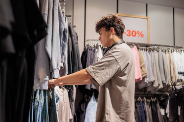 Young Man Choosing Jeans in a Clothing Store. Modern Fashion and Style.  Teen boy 16 years old...