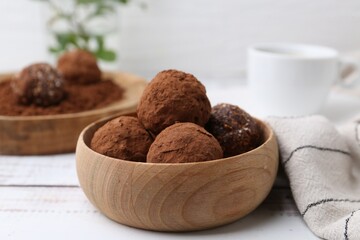 Delicious homemade candies with cocoa powder on white wooden table, closeup