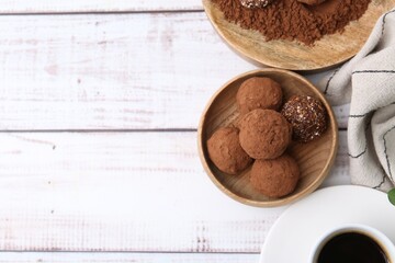 Delicious homemade candies with cocoa powder and coffee on white wooden table, flat lay. Space for text