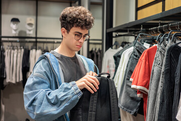 Teenage Boy Choosing a New Backpack in a Clothing Store. Back to School and Urban Lifestyle.  Youth fashion and style. Shopping and retail.  