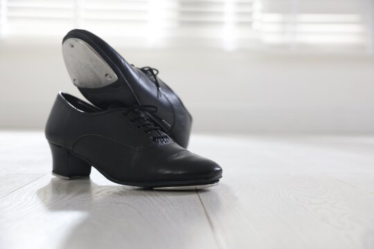 Pair of shoes for tap dance on floor indoors, closeup. Space for text