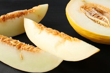 Cut ripe melon on black wooden table, closeup