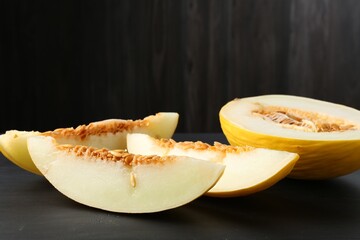 Cut ripe melon on black wooden table, closeup