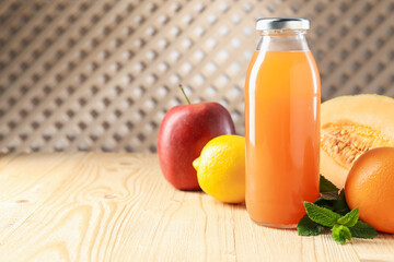 Tasty juice in glass bottle, fresh fruits and mint on wooden table indoors, closeup. Space for text