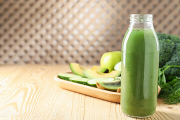 Tasty juice in glass bottle and ingredients on wooden table indoors, closeup. Space for text