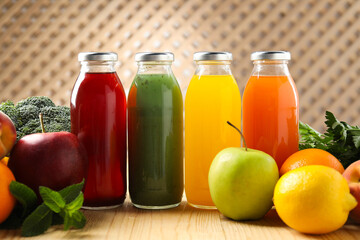 Tasty juices in glass bottles, fresh ingredients and mint on wooden table indoors, closeup