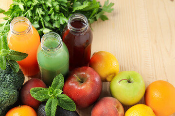 Tasty juices in glass bottles, fresh ingredients and herbs on wooden table, closeup