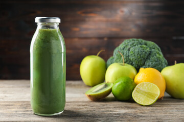 Tasty juice in glass bottle and fresh ingredients on wooden table against brown background, closeup