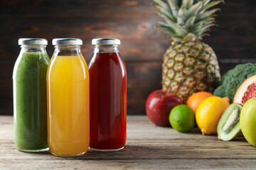 Tasty juices in glass bottles and fresh ingredients on wooden table against brown background, closeup