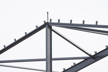 Metal construction, in the photo the structure of the building frame made of metal beams against the background of a gray sky