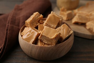 Homemade caramel candies in bowl on wooden table, closeup