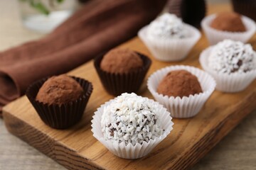 Delicious homemade candies with cocoa powder and coconut flakes on table, closeup