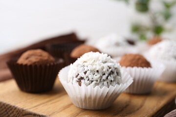 Delicious homemade candies with cocoa powder and coconut flakes on table, closeup