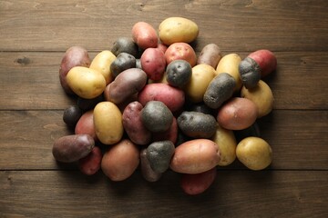 Different types of potatoes on wooden table, flat lay