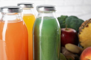 Tasty juices in glass bottles and ingredients on blurred background, closeup