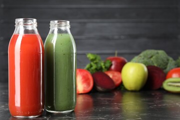 Tasty juices in glass bottles and ingredients on black marble table, closeup
