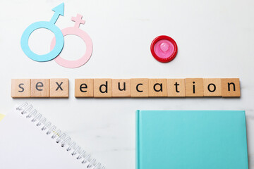 Phrase Sex Education made with wooden letters, condom, paper female and male gender symbols,...