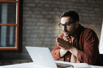 Businessman having video call on laptop in office, professional manager working remotely