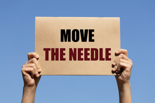 Move the needle text on paper holding by a woman's hand with blue sky background