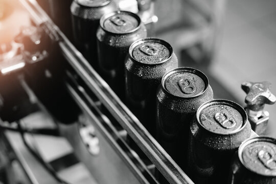 Industrial beer canning line with freshly sealed beverage cans in drink factory