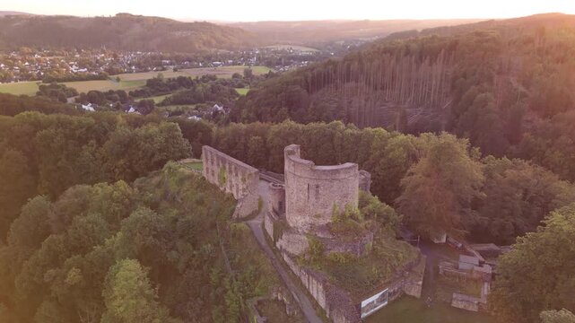 Forward drone flight towards Windeck Castle ruins in North Rhine-Westphalia, Germany, with smooth tilt down to reveal medieval tower and historic stone architecture