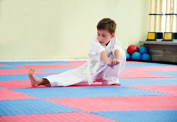 Karate boy doing stretching at workout.Child in kimono. Martial arts. 極真会(Karate Kyokushin)	
