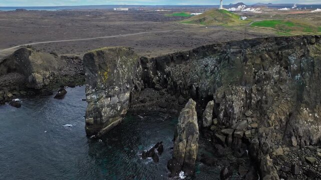Basalt rock pillars by the ocean, Iceland&rsquo;s south coast. Aerial 4K drone footage shows rugged sea stacks and waves crashing against cliffs.
