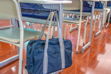 スクールバックの掛った教室にある机と椅子の後方からのクローズアップ、学校イメージ