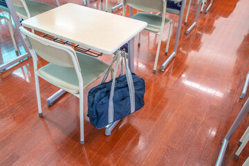 スクールバックの掛った教室にある机と椅子の後方からのクローズアップ、学校イメージ