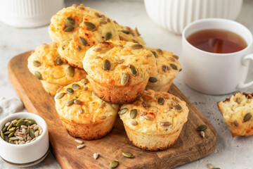 Savory zucchini muffins with cheese and seeds on wooden board on white kitchen table background. Healthy and quick morning breakfast