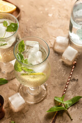 Mojito long rum drink with fresh mint, lemon juice, ice cubes and soda on brown textured background. Summer party cocktails