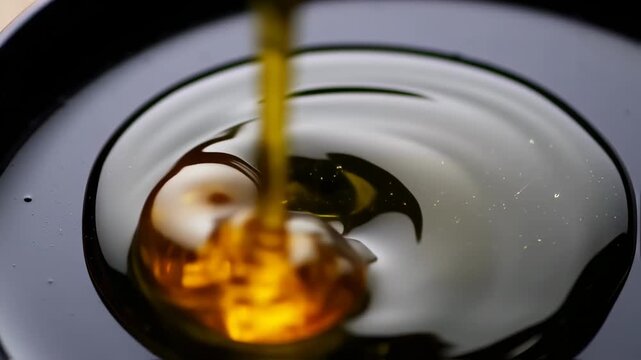 Pouring Golden Liquid on Black Surface Creates Mesmerizing Visual Effect, perfect for Cooking videos