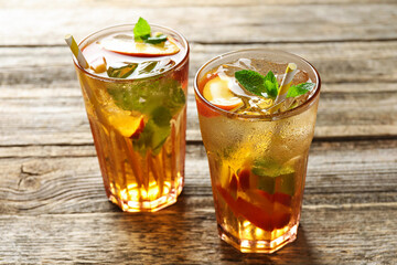 Refreshing iced peach tea in glasses on wooden table, closeup
