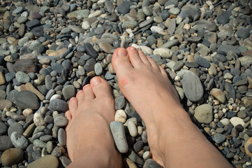 close-up - female legs on a pebble beach by the sea