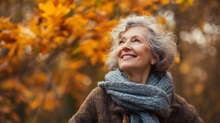 Portrait of an elderly happy smiling woman in autumn park, positive cheerful aged lady enjoying a walk outdoors in autumn forest