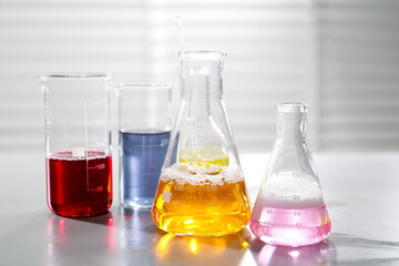 Laboratory glassware with different samples on light table indoors, closeup. Solution chemistry