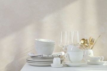Different clean white dishware and glasses on counter in kitchen, space for text