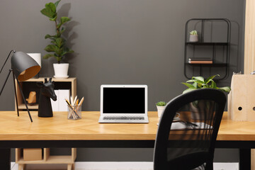 Stylish workplace with laptop and stationery on wooden table in office