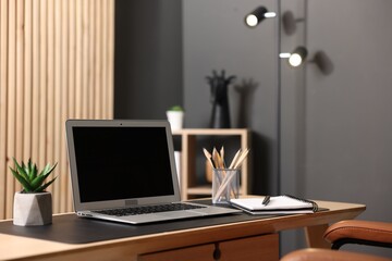 Stylish workplace with laptop and stationery on wooden table in office